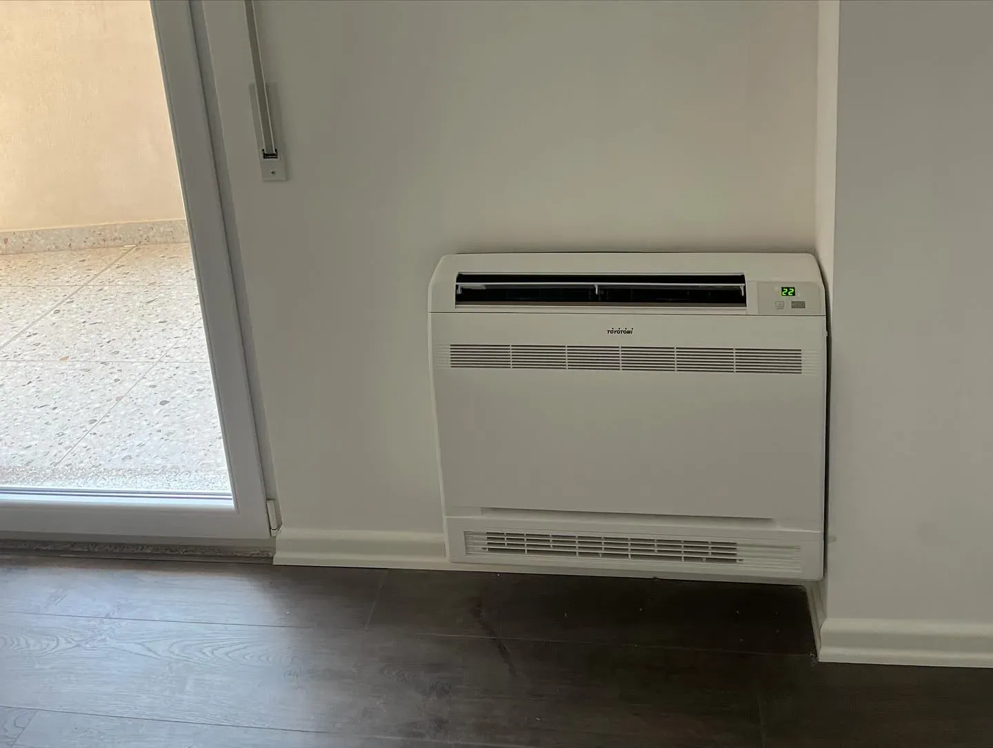 Kondicioner dyshemeje i instaluar pranë dritares në një apartament